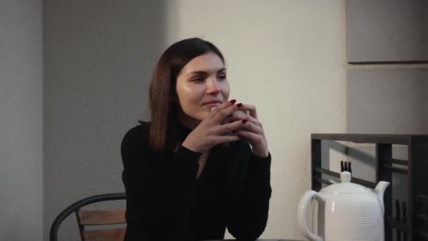 Young beautiful woman sitting home in chair by window with cup of hot coffee — Video Stock