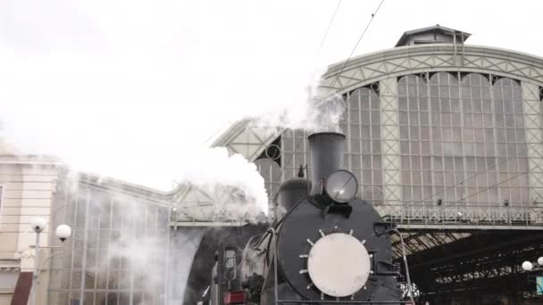 O trem a vapor retro parte da estação ferroviária. Velho trem a vapor preto com carros azuis — Vídeo de Stock