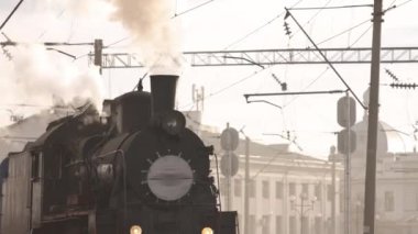 Retro buhar treni tren istasyonundan ayrılıyor. Mavi arabalı eski siyah buhar treni