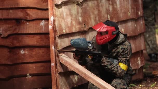 Paintball jugador deportivo con máscara protectora apuntando refugio de armas bajo ataque — Vídeos de Stock