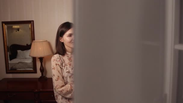 Young happy brunette woman standing near opened curtains window looking outside — Stock Video