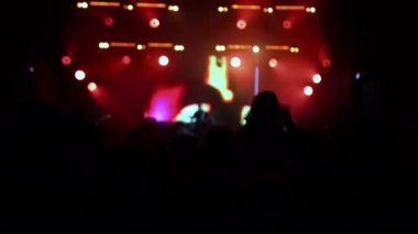 Parlak ışıklarla rock resitalinde tezahürat yapan kalabalık. Konser kalabalığı siluetleri