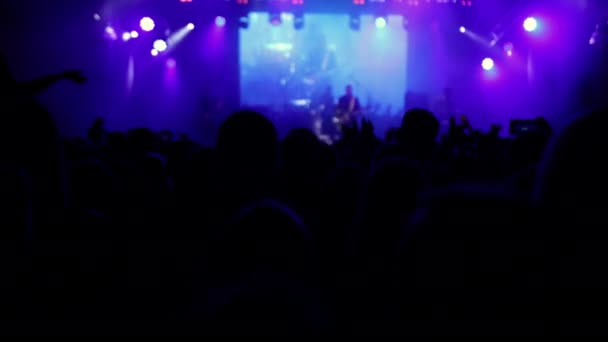 Aydınlatılmış sahne ışıkları. Kaldırılan eller görülebilir. Konser kalabalığı siluetleri — Stok video