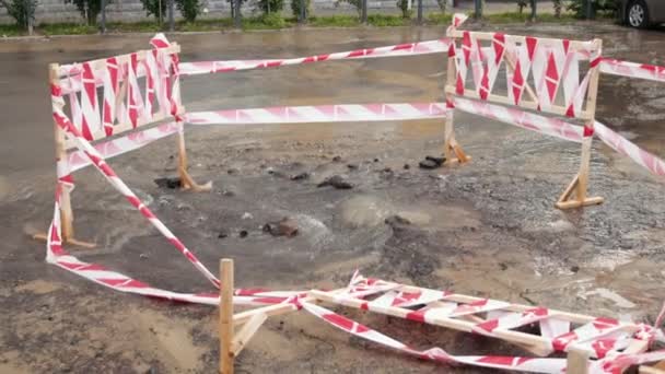 Vägen sprutar vatten bredvid trafikkoner. Pölar som orsakar skador på asfalt. Avloppssystem — Stockvideo