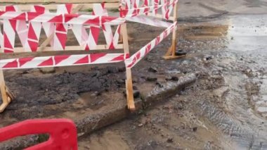 Trafik konilerinin yanında yol suyu fışkırır. Su birikintisi asfalta zarar veriyor. Kanalizasyon