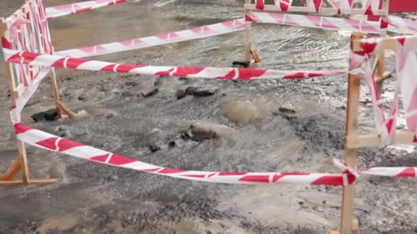 Sewerage, hydro board. Danger border near water leak on road. Road spurt water — Stock Video