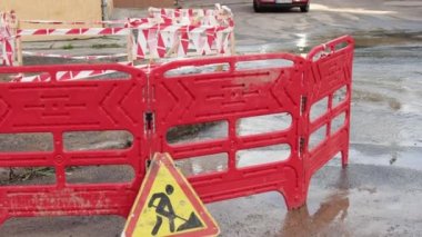 Trafik konilerinin yanında yol suyu fışkırır. Su birikintisi asfalta zarar veriyor. Kanalizasyon