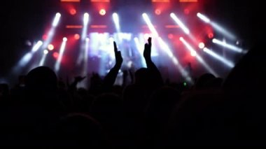 Parlak ışıklarla rock resitalinde tezahürat yapan kalabalık. Konser kalabalığı siluetleri