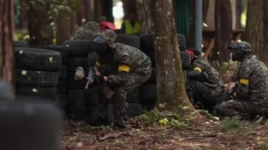 Koruyucu maske takan paintball oyuncusu silah barınağı saldırısını hedefliyor