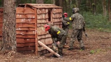 Koruyucu maske takan paintball oyuncusu saldırı altında silah barınağını hedefliyor