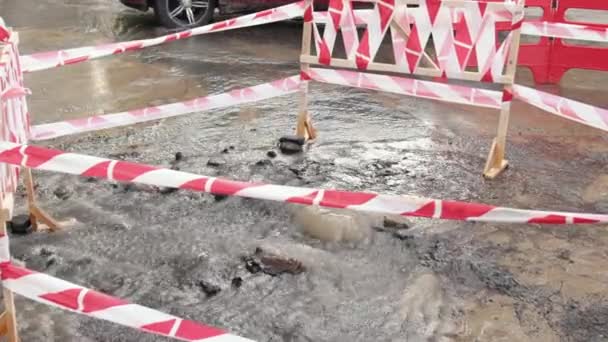 Sewerage, hydro board. Danger border near water leak on road. Road spurt water — Stock Video