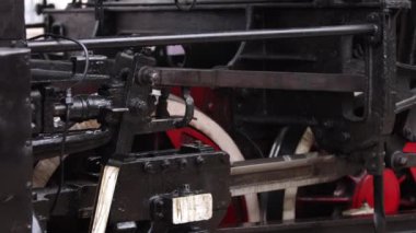 Eski tekerlekler ve buhar makinesinin parçaları. Sovyet lokomotifi duruyor