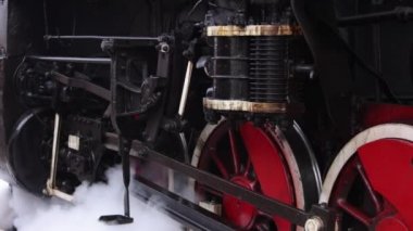 Eski tekerlekler ve buhar makinesinin parçaları. Sovyet lokomotifi duruyor