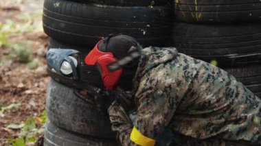 Yüksek kalite. Paintball oyuncusu koruyucu maske takıyor ve nişan alıyor. Ateş edildi.