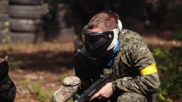 Портрет американского пейнтболиста в маске, который целится в противников на войне — стоковое видео