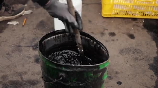Menschliche Hand mischt schwarzes Öl in Fässern als Zutat für Molotow-Cocktails. — Stockvideo