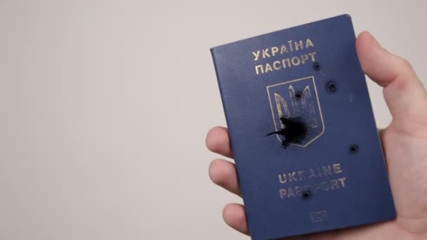 Mans Hand hält einen ukrainischen Pass, der mit Kugeln beschossen wurde. Konzept des Krieges in Russland — Stockvideo