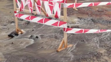 Trafik konilerinin yanında yol suyu fışkırır. Su birikintisi asfalta zarar veriyor. Kanalizasyon