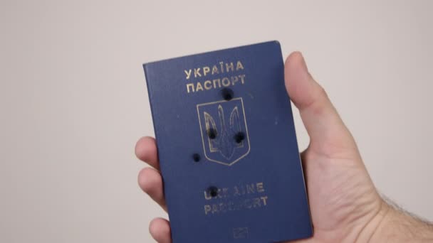 Украинский паспорт с мужской рукой. Дыры в документе от выстрелов. Война — стоковое видео