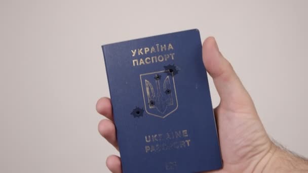 Ukrainskt pass som innehas av män hand. Hål i dokumentet från skottlossning. Krig — Stockvideo
