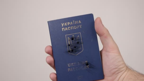 Ukrainskt pass som innehas av män hand. Hål i dokumentet från skottlossning. Krig — Stockvideo