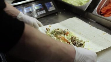 Erkeklerin elleri sulu shawarma pişiriyor. Baharatlı etli leziz donör kebabı.