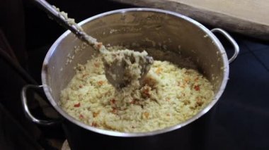 Gönüllü kadın eli, tahta kaşıkla pirinç lapası karıştırıyor. Yardım kavramı