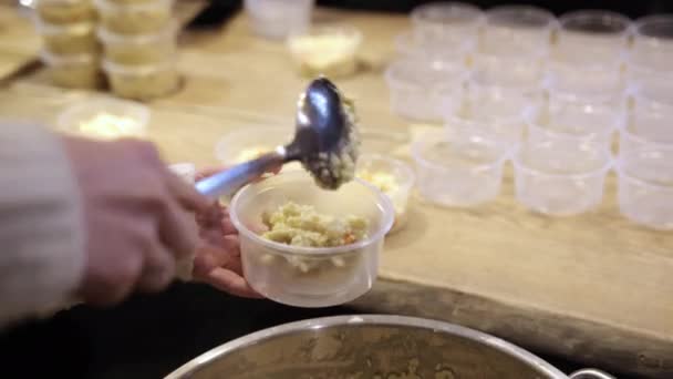 Weibliche Hand füllt Plastikschalen mit Reisbrei, um Obdachlosen zu helfen — Stockvideo