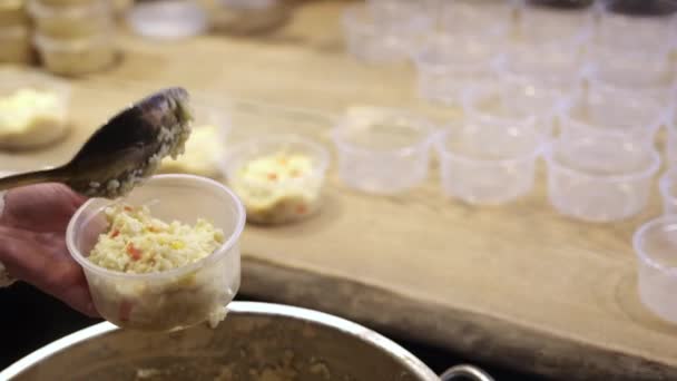A női kéz rizszabkásával tölti meg a műanyag tálakat, hogy segítsen a hajléktalanoknak. — Stock videók