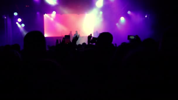 Parlak sahne ışıkları önünde konser kalabalığı siluetleri. İnsanların silueti — Stok video