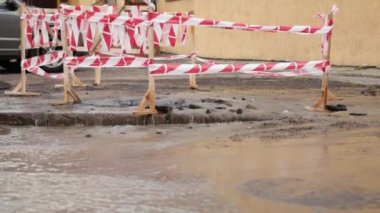 Trafik konilerinin yanında yol suyu fışkırır. Su birikintisi asfalta zarar veriyor. Kanalizasyon