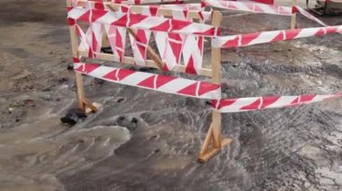 Trafik konilerinin yanında yol suyu fışkırır. Su birikintisi asfalta zarar veriyor. Kanalizasyon