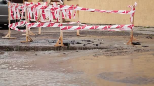 Wegspurt water naast verkeerskegels. Puddle veroorzaakt schade aan asfalt. Riolering — Stockvideo