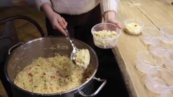 Primo piano di una mano di donne che raccoglie il porridge di riso da grande vaso in ciotole di plastica — Video Stock