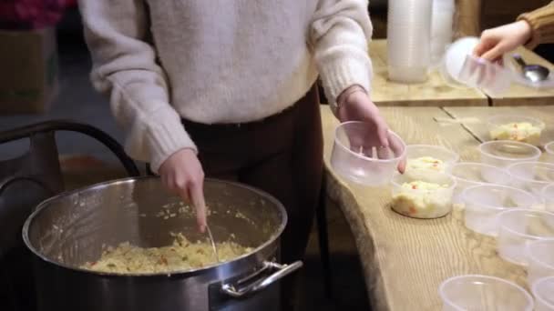 Mão feminina enche tigelas de plástico com mingau de arroz para ajudar os sem-teto — Vídeo de Stock