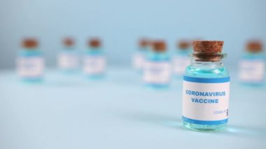 Şırınga iğnesi, bir damla sıvı, mavi arka planda bulanık pfizer şirketi..