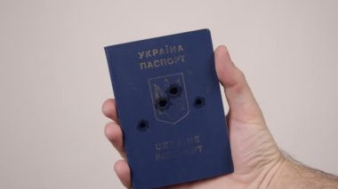 Ukrayna pasaportu bir erkeğin elinde. Belgede silah seslerinden oluşan delikler var. Savaş
