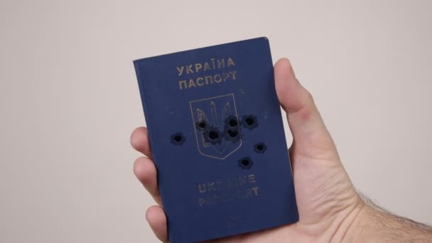 Mano de hombre sostiene pasaporte Ucrania disparado con balas. Concepto de guerra en Rusia — Vídeo de stock