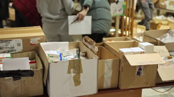 Yakın plan. Gönüllülerden oluşan bir grup, yardım paketleri ve ihtiyaç sahipleri için kutular hazırlıyor. — Stok video
