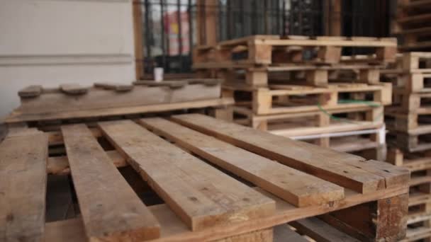 Dřevěné palety naskládané podél zdi na skladišti. Hromady palet. — Stock video
