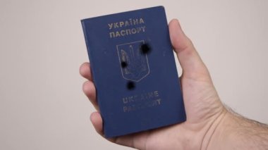 Ukrayna pasaportu bir erkeğin elinde. Belgede silah seslerinden oluşan delikler var. Savaş