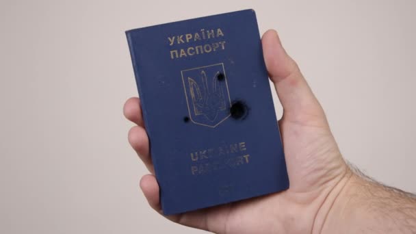 Mano de hombre sostiene pasaporte Ucrania disparado con balas. Concepto de guerra en Rusia — Vídeo de stock