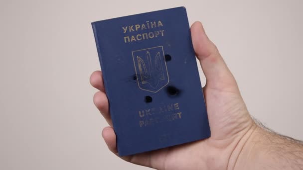 Ukrajinský pas v držení lidí rukou. Díry v dokumentu ze střelby. Válka