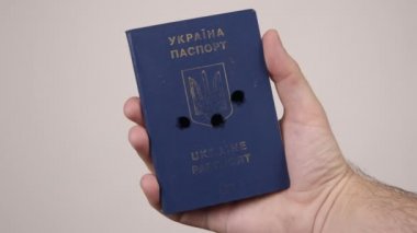 Ukrayna pasaportu bir erkeğin elinde. Belgede silah seslerinden oluşan delikler var. Savaş