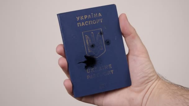 Mans Hand hält einen ukrainischen Pass, der mit Kugeln beschossen wurde. Konzept des Krieges in Russland — Stockvideo