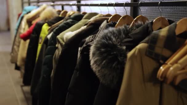 Många mänskliga jackor hänger på hängslen, tomma hängslen i förgrunden. Garderob. — Stockvideo