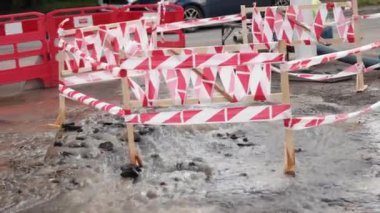 Trafik konilerinin yanında yol suyu fışkırır. Su birikintisi asfalta zarar veriyor. Kanalizasyon