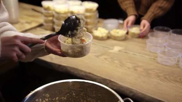 Close-up van met de hand geplukte womans rijstpap uit grote pot in plastic kommen — Stockvideo