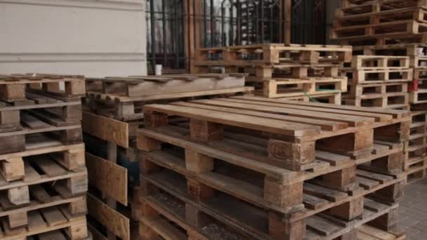 Houten pallets, opgestapeld langs een muur in een pakhuis. Stapels pallets. — Stockvideo