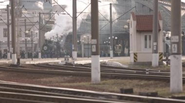 Retro buhar treni tren istasyonundan ayrılıyor. Mavi arabalı eski siyah buhar treni